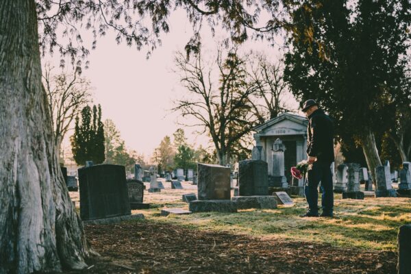 man in black jacket standing in front of grave